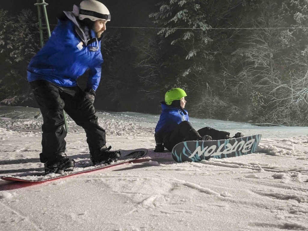 Forest Jade, an instructor at Mount Snow, helps a student with snowboarding at Living Memorial Park in Brattleboro in January 2023-vermont country magazine