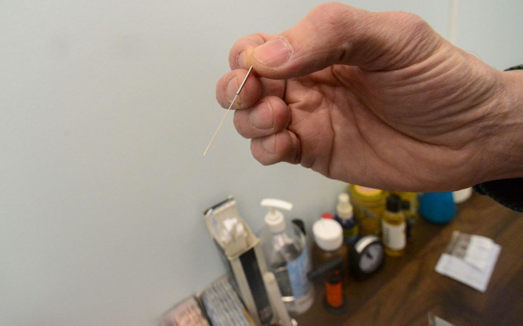 Stefan Grace, a licensed acupuncturist and owner of Confluence Acupuncture in Brattleboro, holds an acupuncture's needle to show how thin it is. Kristopher Radder — Vermont Country. 
