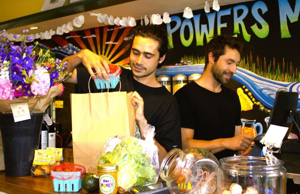 Max Perry and Will Thomas work the front counter at Powers Market. Danielle M. Crosier — Vermont Country-Powers Market-North Bennington-Best Country Stores.