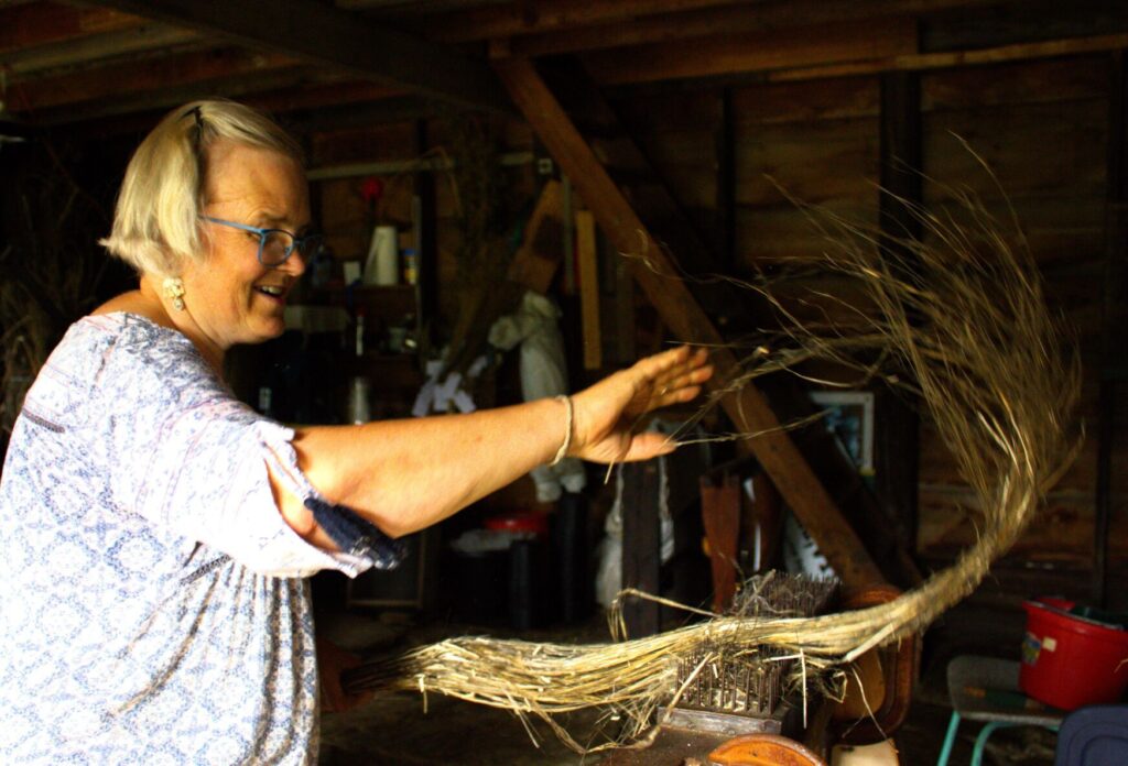 Danielle M. Crosier — Vermont Country Andrea Myklebust, having cleaned the boon from the flax fiber through a process of braking and scutching, runs the fibers through the hackles.